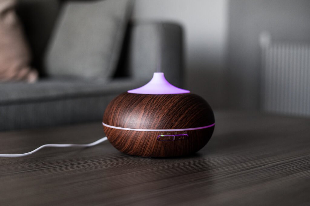 Modern air diffuser on table Modern air diffuser releasing mist on a wooden table in a cozy living room, 2025 model